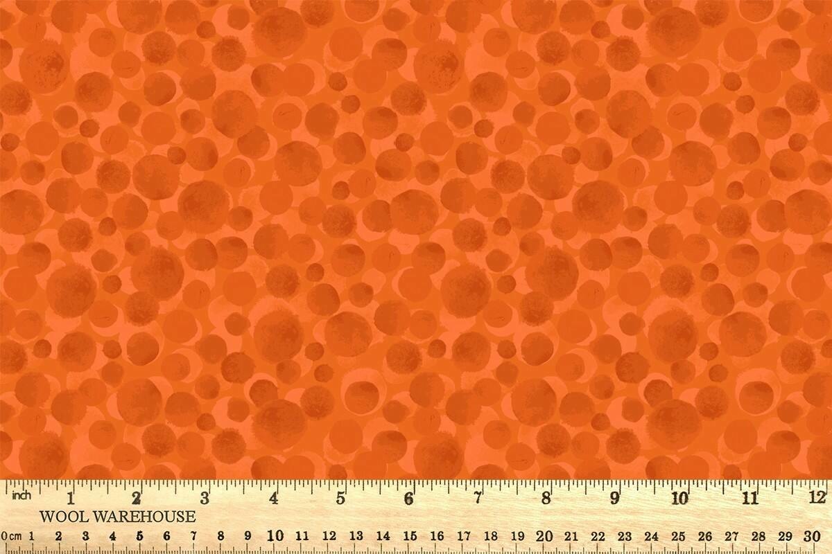 Orange fabric with circular patterns and a ruler at the bottom for scale.